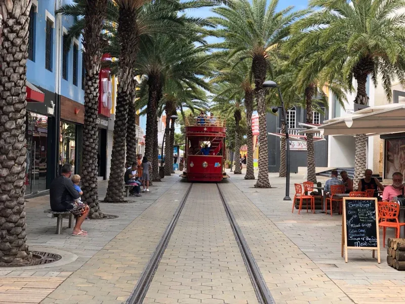 A tramway line in Aruba passes through a retail shopping district with patio seating