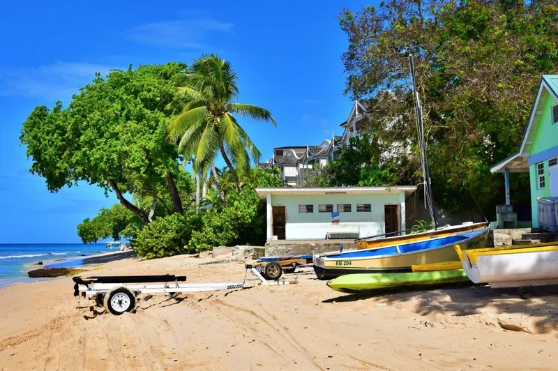 A beachside boat dock in Barbados next to a sandy beach and a house
