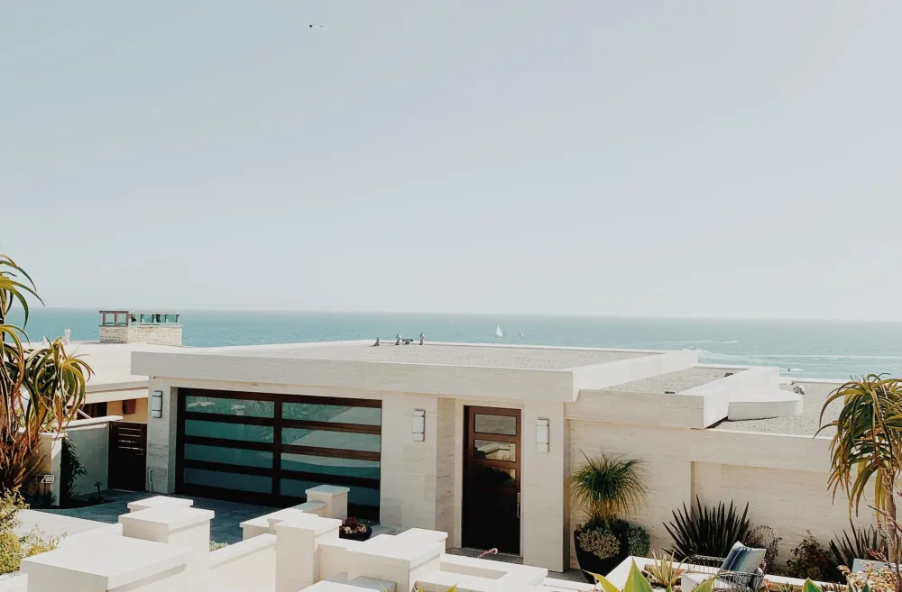 A modernist white beach house near the ocean with palm trees